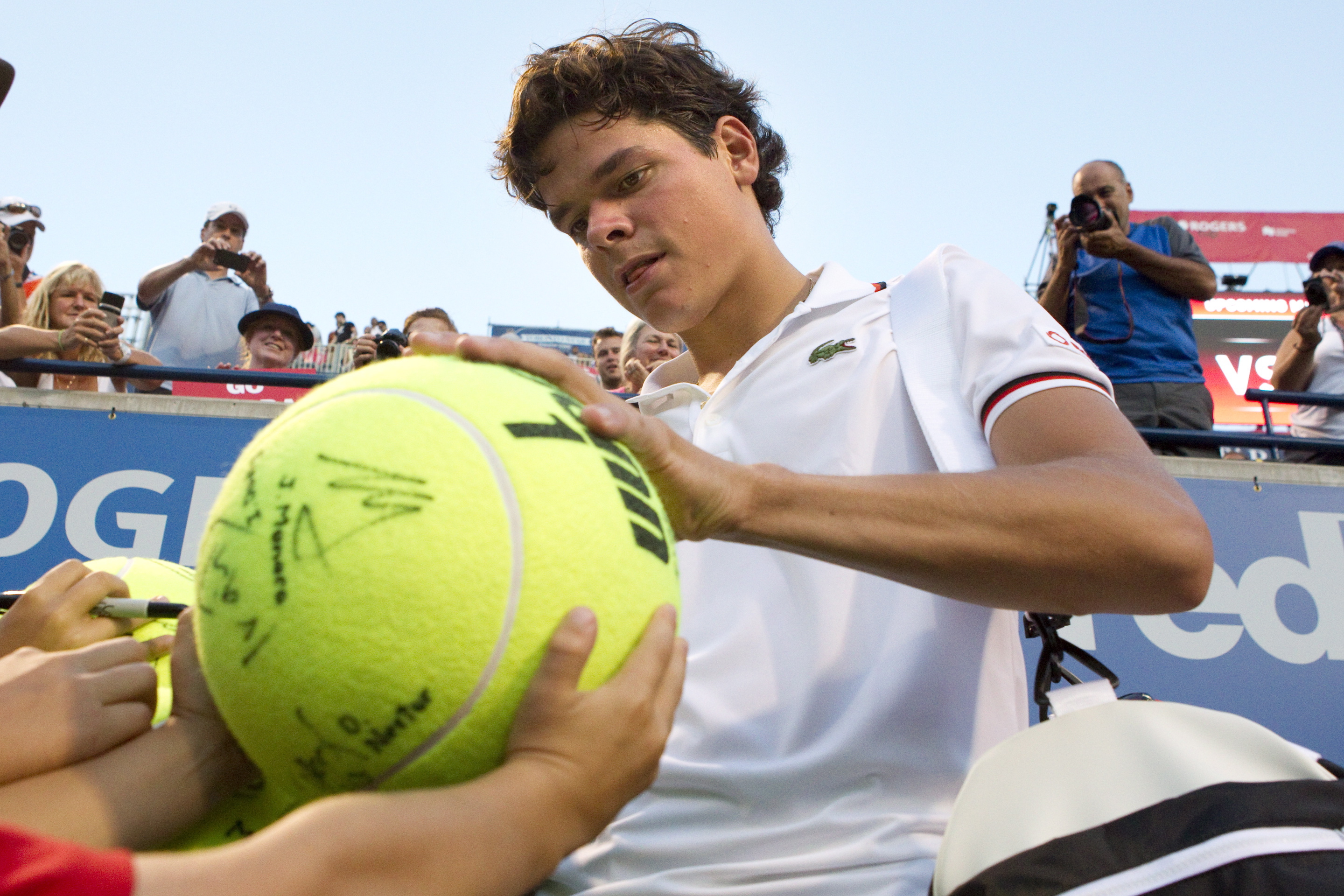Canada's Milos Raonic signs autographs following his 6-3 6-4 win over Serbia's Viktor Troicki during the Rogers Cup in Toronto on Tuesday August 8, 2012. THE CANADIAN PRESS/Chris Young