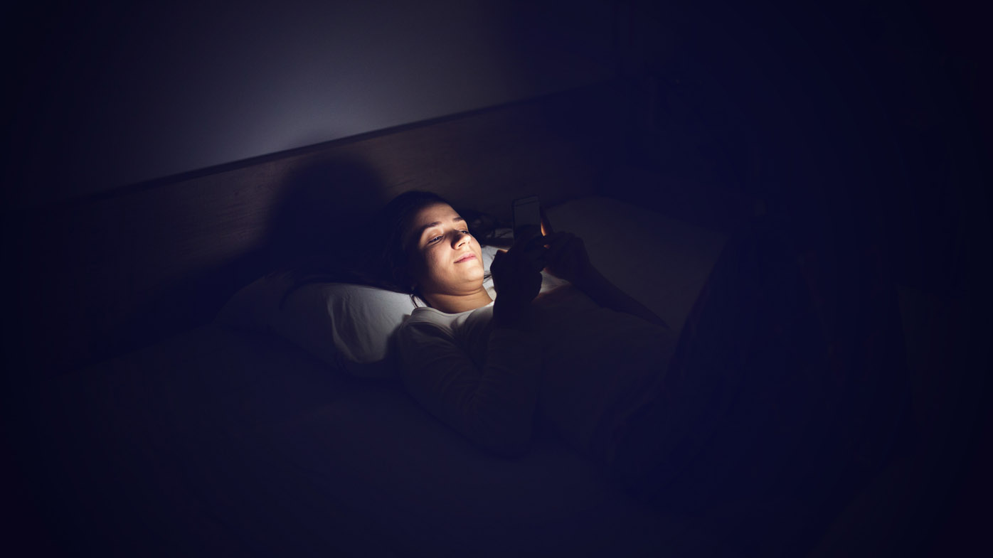 Young beautiful woman lying in bed and texting sms, lifestyle concept