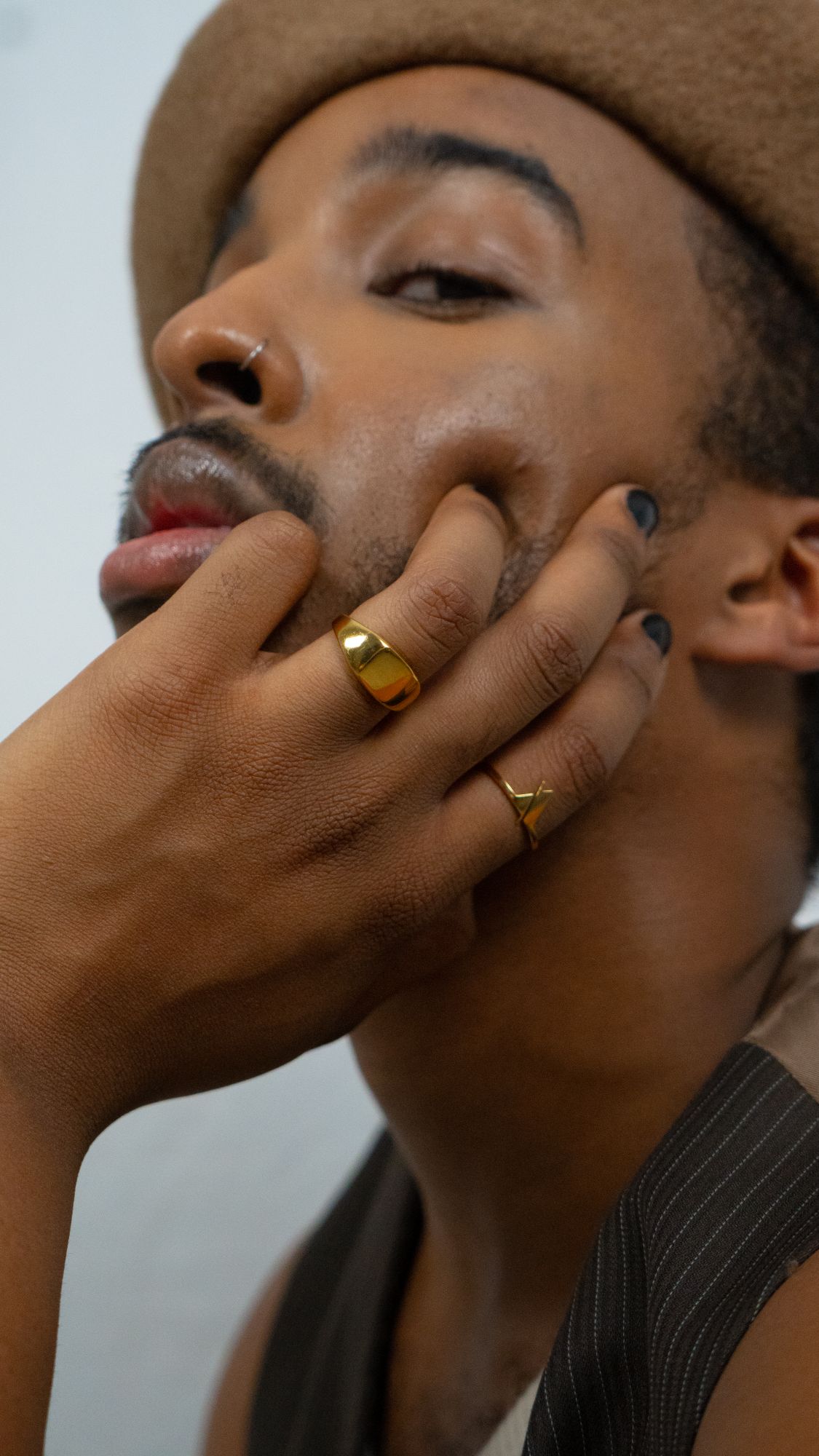 A man with two gold rings touching his cheek.